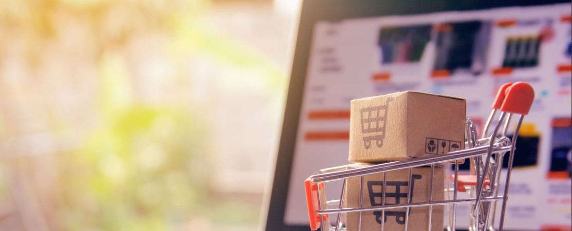 Panier miniature avec colis devant un site e-commerce sur ordinateur